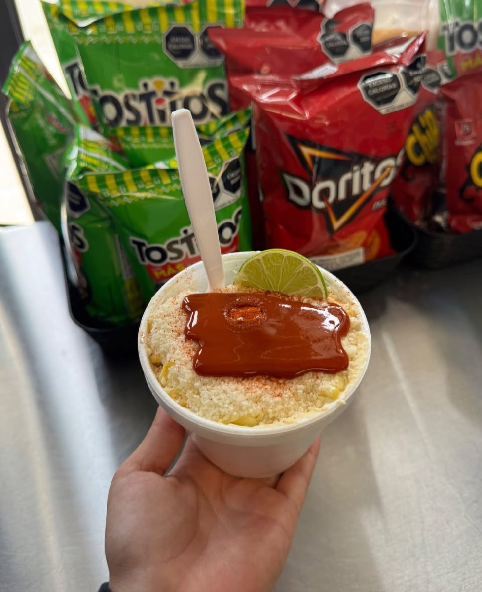 Cup of esquites topped with cotija cheese, chile and a lime wedge