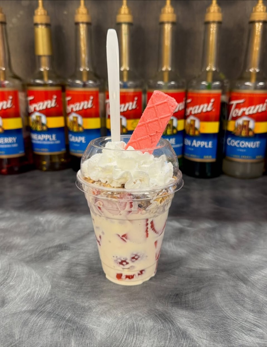 Fresas con crema in a clear cup with whipped cream and a strawberry wafer